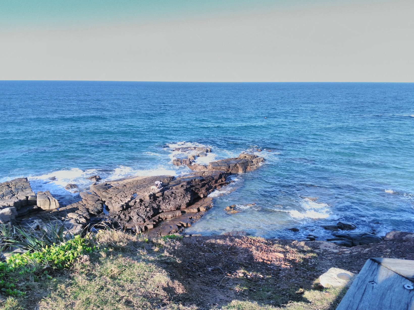 a small rocky cliff stretches into a wide ocean